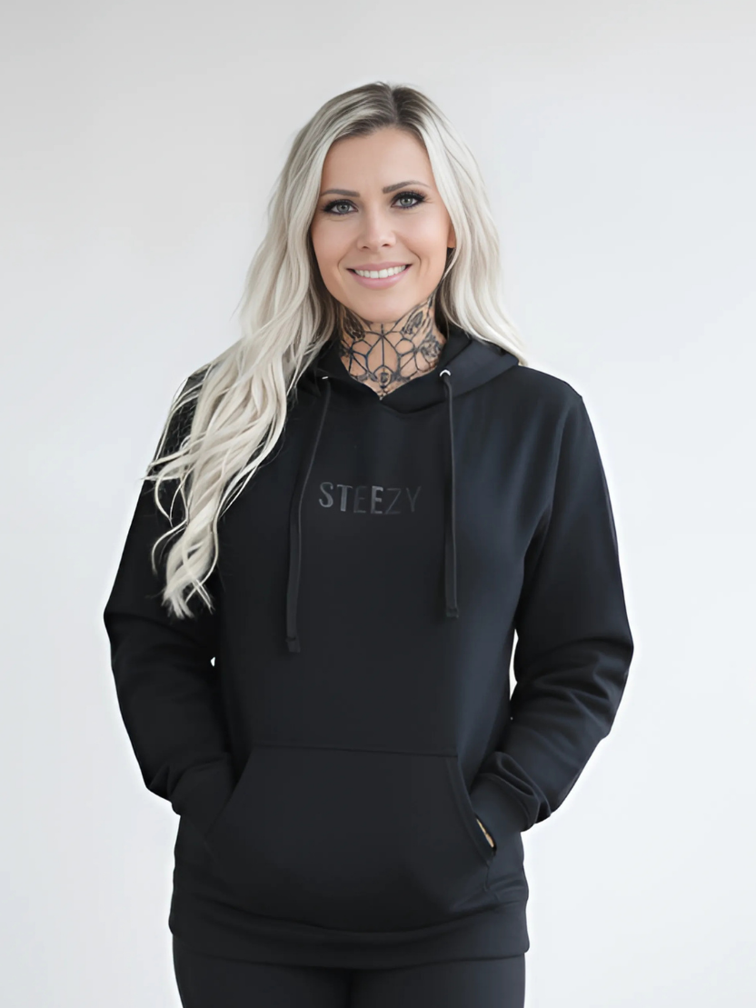 Woman wearing a black hoodie with 'STEEZY' logo on a white background